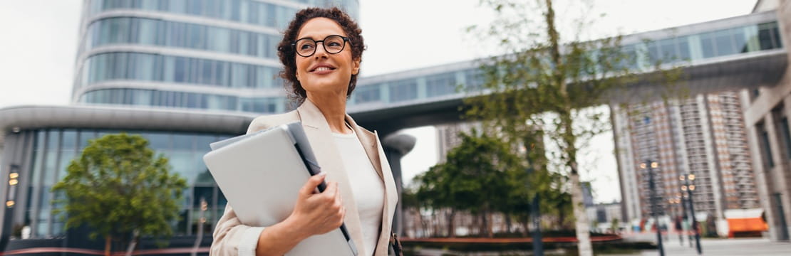 Business owner walking through a modern city with a laptop, representing how a strong digital presence supports business success.